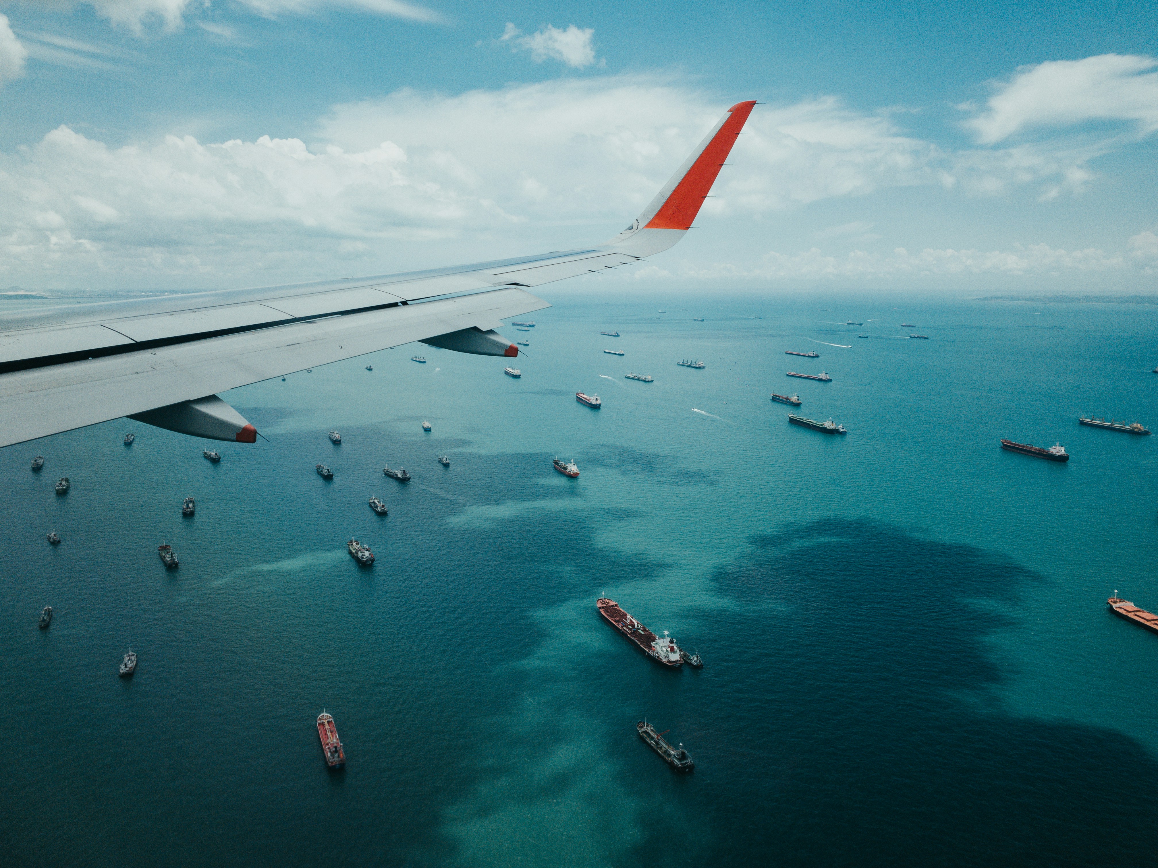 View from an aircraft wing over a busy shipping lane, air and sea freight