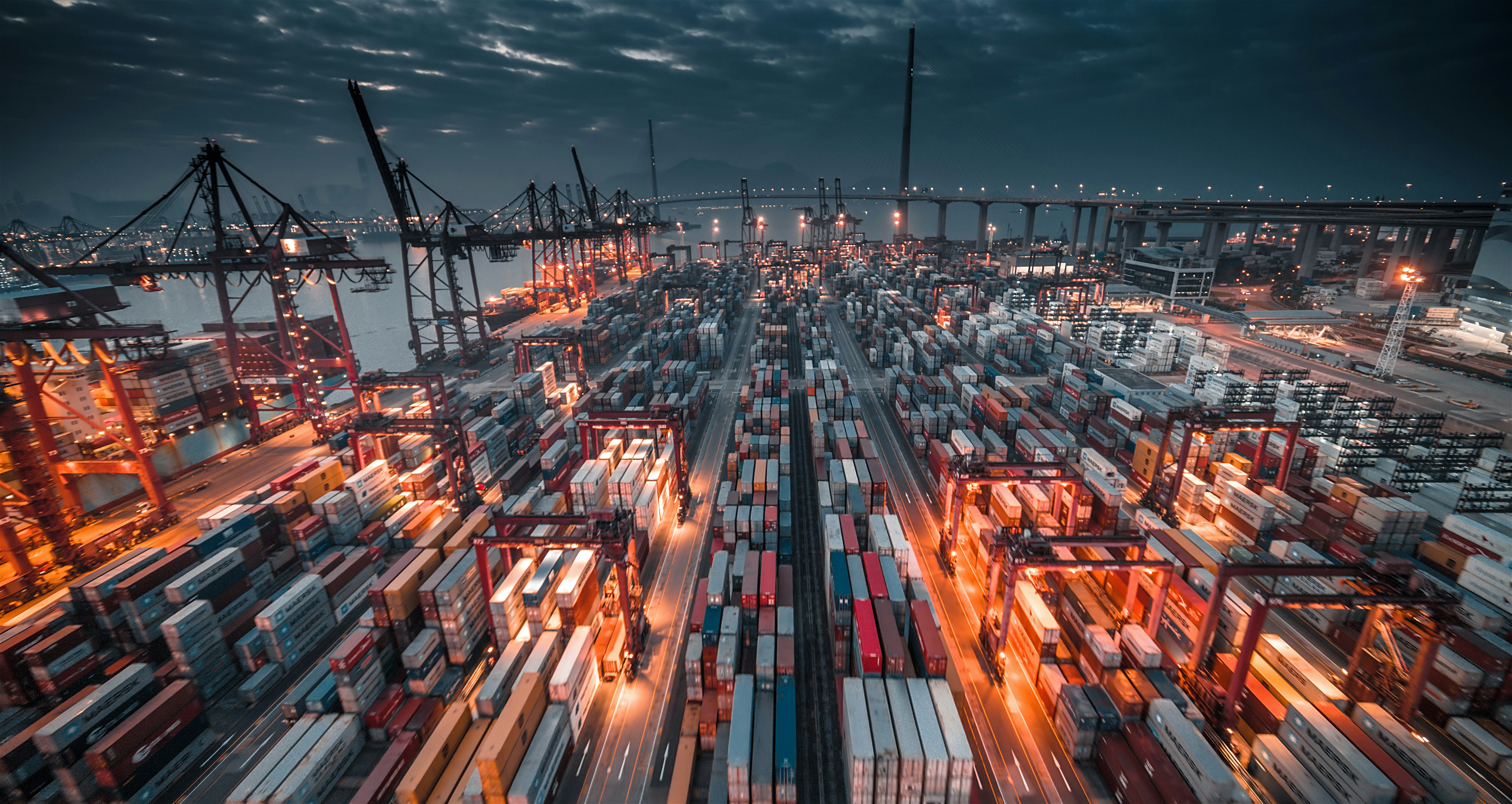 Container port terminal at night with cranes and stacked containers